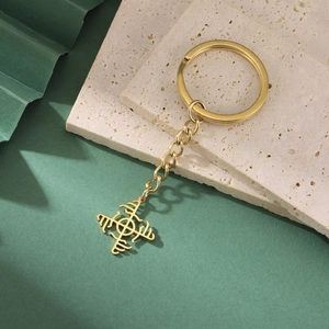Detail of a golden Nordic Viking compass keychain on a natural stone surface