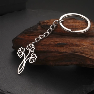 Gros plan d'un porte-clés en acier inoxydable argenté avec pendentifs triple lotus sur bois