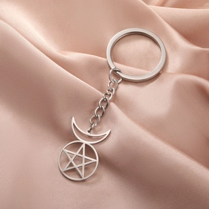 Minimalist stainless steel pentagram moon keychain on pink satin background
