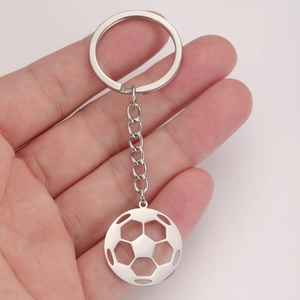 Main tenant un porte-clés pendentif football ajouré en acier inoxydable poli brillant