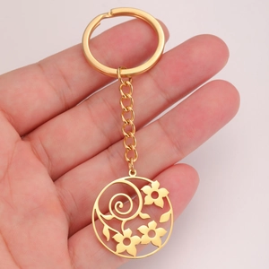 Close-up of golden stainless steel keychain with hollow flower pendant held by hand