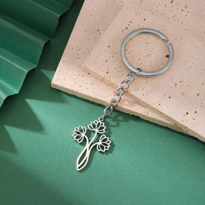 Vue détaillée du porte-clés en acier argenté avec pendentif lotus évidé sur pierre