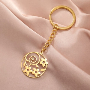 Detail of a gold hollow-out flower pendant keychain on elegant pink silk fabric