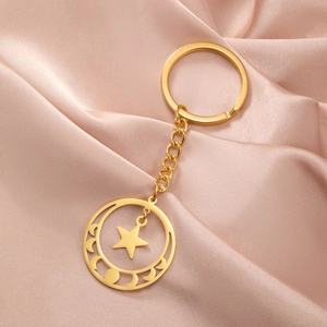 Macro detail of gold pentagram moon phase keychain on elegant silk background