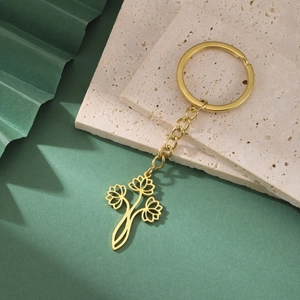 Détail d'un porte-clés en acier inoxydable doré avec pendentif creux de trois fleurs de lotus
