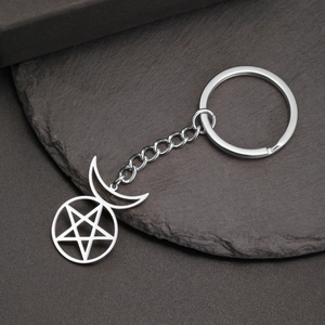 Detailed view of stainless steel pentagram and crescent moon pendant keychain on stone surface
