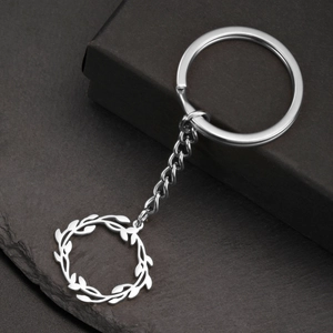 Porte-clés en acier inoxydable poli avec pendentif couronne de feuilles sur fond sombre