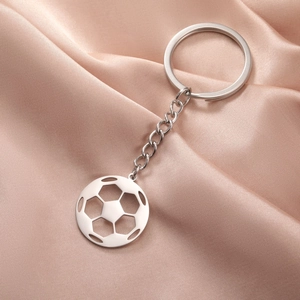 Polished stainless steel soccer ball keychain on champagne satin fabric background