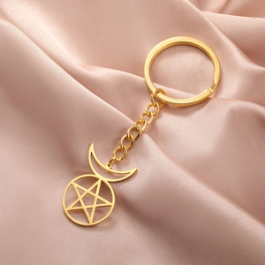 Detailed view of golden pentagram and crescent moon keychain on elegant satin