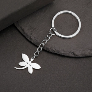 Polished stainless steel dragonfly keychain with silver finish on stone texture