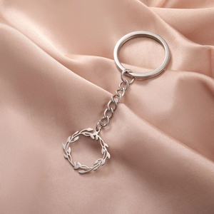 Détail d'un porte-clés en acier inoxydable avec pendentif couronne de feuilles sur soie