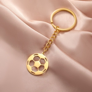 Detail of a hollow soccer ball pendant keychain in golden finish on silk background