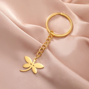 Detailed view of a golden dragonfly keychain on elegant champagne silk fabric background