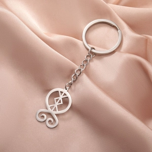 Macro detail of silver stainless steel troll cross pendant on champagne silk background
