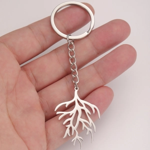 Titanium steel keychain with geometric hollow coral pendant held in hand over pink background