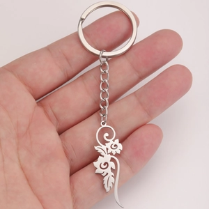 Polished silver stainless steel keychain with hollow floral pattern charm held in hand