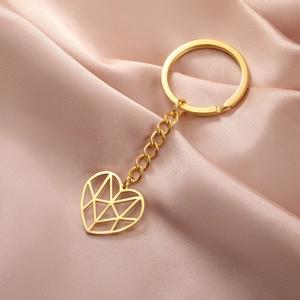 Golden minimalist heart-shaped hollow pendant keychain on elegant pink silk background