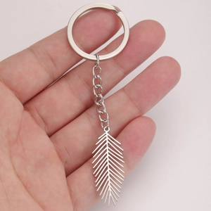 Minimalist stainless steel keychain with hollow feather pendant held in hand for scale