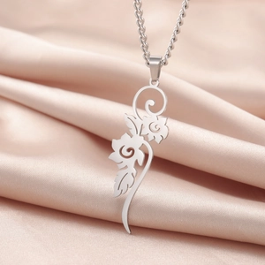Detalle de un collar con colgante floral plateado y calados sobre fondo de satén