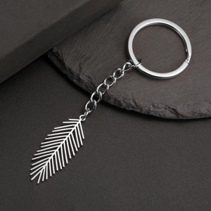 Detail of silver stainless steel keychain featuring a geometric leaf pendant on a rock surface