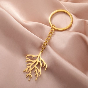 Close-up of golden stainless steel keychain with branch pendant on champagne silk
