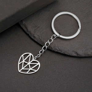Polished silver stainless steel keychain with a geometric hollow heart pendant on slate stone