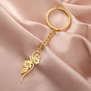 Detailed shot of a gold flower pendant keychain on elegant pink silk background
