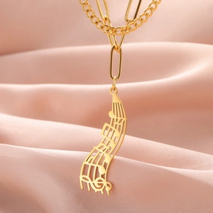 Macro shot of gold stainless steel musical note pendant on a pink silk background