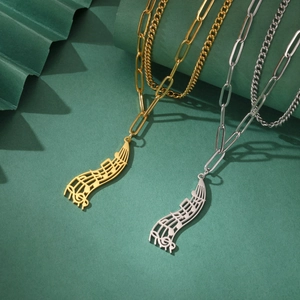 Artistic silver and gold musical note pendants on clip link chains over green paper