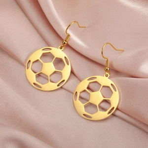 Detail view of golden hollow soccer dangle earrings on soft pink silk background