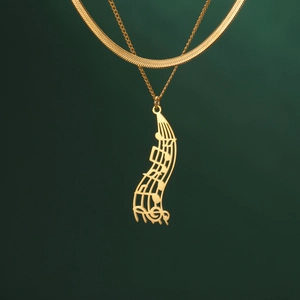 Close-up of double-layer gold snake chain necklace with musical note waterfall pendant