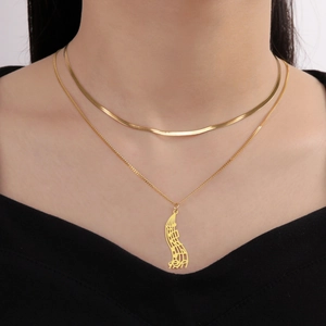Detail shot of a double-layered gold stainless steel necklace with musical note pendant
