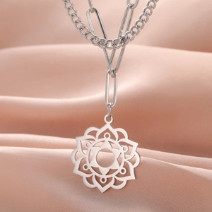 Detail of silver mandala pendant with geometric stainless steel link chain on pink silk