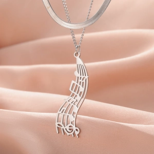 Detailed close-up of musical note pendant necklace on orange silk fabric