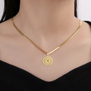 Close-up of a gold mandala pendant on a flat snake chain worn by a model