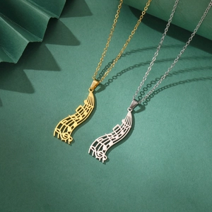 Close-up of gold and silver stainless steel musical note pendants with cutout sheet music