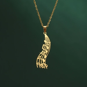 Detail of music note pendant on gold cross chain against dark green backdrop