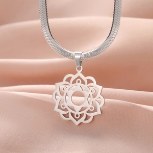 Macro view of silver mandala flower pendant on flat snake chain with satin backdrop