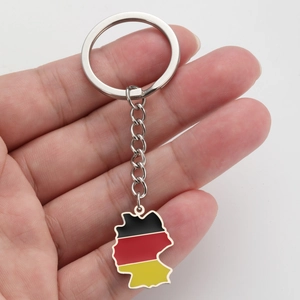 Stainless steel Germany map keychain with flag colors held in hand for scale