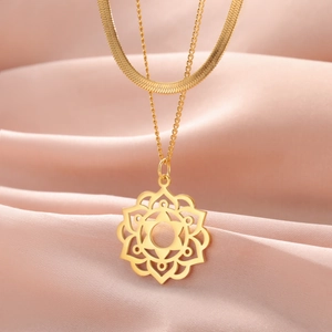 Detail of gold layered necklace with flat snake chain and mandala flower pendant