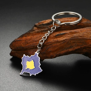 Detail view of Kosovo map keychain with purple enamel finish on dark wooden base
