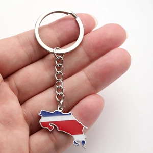 Vue tenue en main du porte-clés carte du Costa Rica avec drapeau émaillé et anneau métal