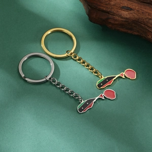 Detailed macro view of gold and silver St. Kitts and Nevis flag map keychains on green surface