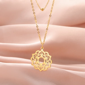 Detailed macro view of a gold mandala flower pendant resting on soft pink silk fabric