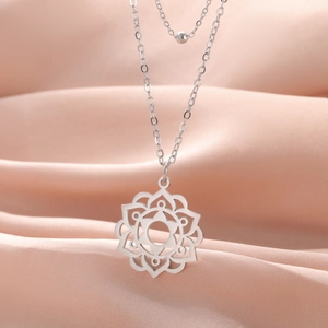 Detailed close-up of a silver mandala pendant on a soft pink satin fabric background