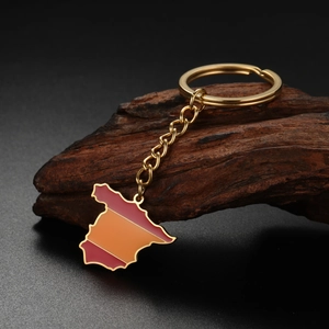 Detailed view of Spain map keychain with red and yellow enamel flag on vintage wood background