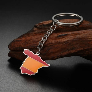 Detail of Spain map keychain with red and yellow enamel colors on a dark wood background