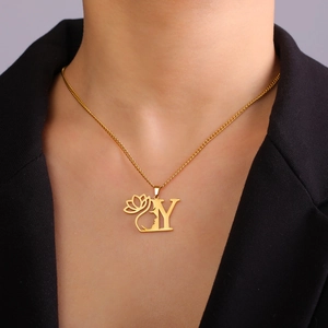 Gros plan du collier doré lettre Y avec pendentif silhouette de lotus et visage