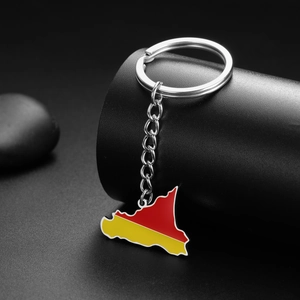 Macro shot of Sicily map keychain with red and yellow enamel on a dark pebble background