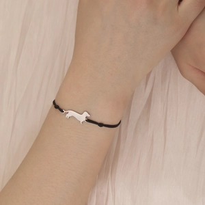 Close-up of a black woven rope bracelet with a stainless steel dachshund charm on a wrist